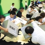 投票用紙を開披台に広げる市職員ら＝三田市三輪、神姫バス城山体育館（撮影・吉田敦史）