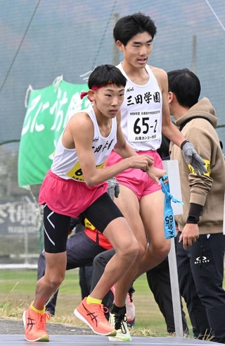 男子・三田学園の３区森田敬太選手（左）にたすきを託す２区大宮玲士選手＝豊岡市日高町（撮影・大田将之）