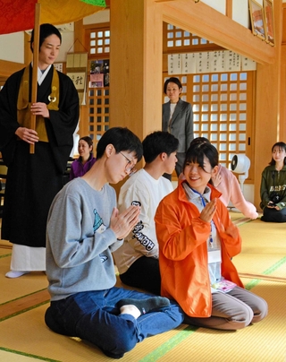 大阪成蹊大の学生から説明を聞きながら座禅に取り組む参加者ら＝三田市桑原