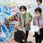 三田署員（右奧）に付き添われ、電器店で電話機を選ぶ利用者＝三田市けやき台１