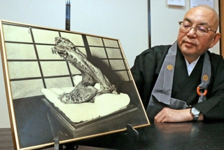 「蛇の頭」の写真を眺める欣勝寺の谷口真弥住職＝三田市桑原