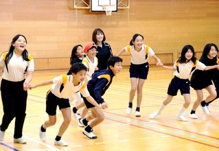 ゲームを通じて大竹七未さん（中央）と交流を深める児童たち＝学園小学校