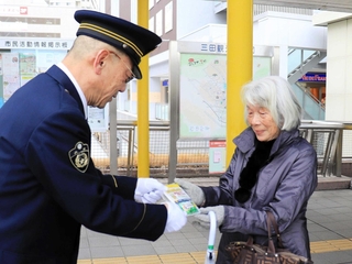 特殊詐欺への注意を呼びかけながら啓発グッズを手渡す齋藤健司署長（左）＝三田市駅前町
