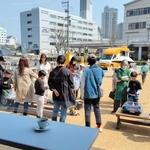 三田市のフラワータウンで開かれる喫茶イベントに合わせ、保護者発案のベーゴマ遊びを楽しむ大人と子どもら