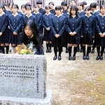 事故で亡くなった石井勝さんを悼み、顕彰碑に献花する山橋未央部長（手前中央）と部員たち＝三田市南が丘２