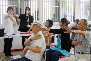 作業療法士の河島くにみさん（左奥）から認知機能を鍛える体操を教わる参加者たち＝三田市弥生が丘１
