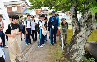 県自然保護協会の山崎紫副理事長（右）から、クビアカツヤカミキリの痕跡を探す方法について解説を聞く高校生ら＝三田市下相野