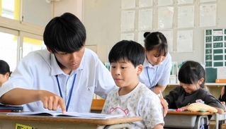 夏休みの宿題に取り組む三田小の児童をサポートする有馬高生＝三田市屋敷町