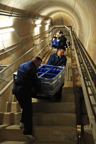 ダム内部の通路に酒を運び込む小西酒造の従業員ら＝３月５日、三田市加茂、青野ダム（撮影・吉田敦史）