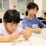 砂浜に落ちていたプラスチックごみなどを使い、キーホルダーを作る子どもたち＝三田市学園上ケ原