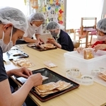 クッキーに食品表示ラベルを貼る「のぞみ」のメンバーら＝三田市上井沢