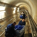 ダム内部の通路に酒を運び込む小西酒造の従業員ら＝３月５日、三田市加茂、青野ダム（撮影・吉田敦史）