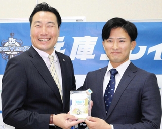 阪神スカウトの筒井和也さん（左）から、記念品としてドラフト会議のＩＤパスを受け取った山崎照英選手＝三田市天神１
