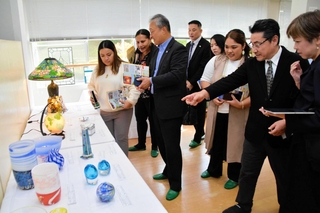 三田市ガラス工芸館の元廣幸雄館長（右から２人目）から、ガラス作品について話を聞く参加者ら＝三田市香下
