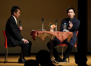 恩師の大井浩さん（左）と壇上で掛け合う山田拓朗さん＝三田市武庫が丘７