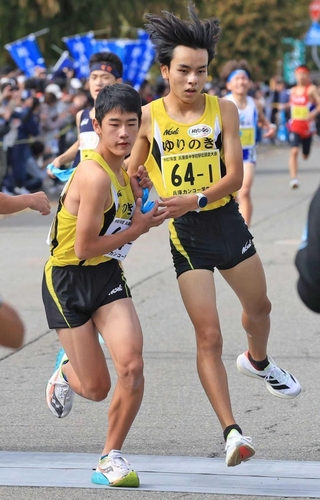 ゆりのき台の１区森本凌馬選手（右）から３位でたすきを受け取る２区法貴健人選手＝豊岡市日高町（撮影・吉田敦史）