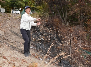 車両火災の発生現場で、救助時の様子を振り返る竹内幹雄さん＝三田市福島