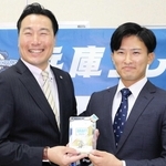 阪神スカウトの筒井和也さん（左）から、記念品としてドラフト会議のＩＤパスを受け取った山崎照英選手＝三田市天神１