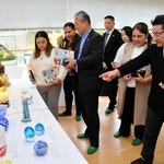 三田市ガラス工芸館の元廣幸雄館長（右から２人目）から、ガラス作品について話を聞く参加者ら＝三田市香下