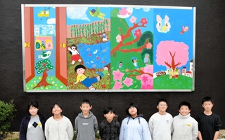 壁に飾られた作品と、中心になって活動した実行委員会のメンバーたち＝三田市三田町