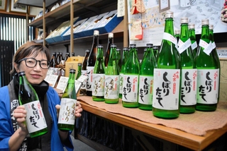 販売の始まった新酒を手にする６代目当主の岡村理恵さん＝三田市木器