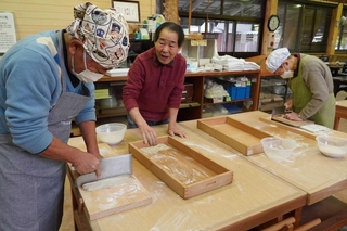 和田良三道場長（中央）の指導を受けながらそば打ちに取り組む岩倉そばの会のメンバー＝三田市永沢寺