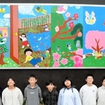 壁に飾られた作品と、中心になって活動した実行委員会のメンバーたち＝三田市三田町