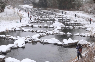 雪が降る渓谷で釣り糸を垂らした参加者＝三田市小柿