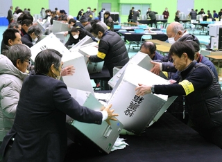 神姫バス城山体育館で行われた三田市の開票作業。市職員らが投票箱の中身を開被台に広げた＝８日夜、同市三輪