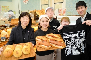 消防車の焼き印入りのパンや、オリジナルＴシャツを手にするモリタホールディングス社員とサンポッポベーカリーのスタッフら＝三田市三輪１