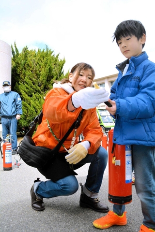 武庫小校区地域防災訓練で、消火器の使い方を教える岡田佳保里さん（中央）＝三田市武庫が丘４