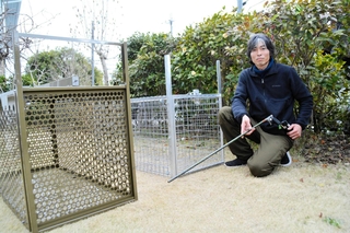 サル捕獲用のおりを前にする三木清雅さん＝三田市内