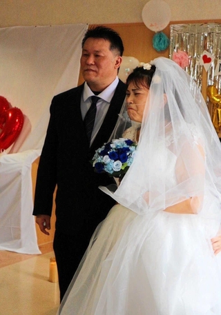 夫の横山康隆さん（左）と並び、涙ぐむ千夏さん。病院スタッフの補助で、立つことができた＝三田市大原（提供）