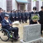 顕彰碑に花を手向けた吹奏楽部員と、犠牲になった石井勝さんの兄の努さん＝三田市南が丘２