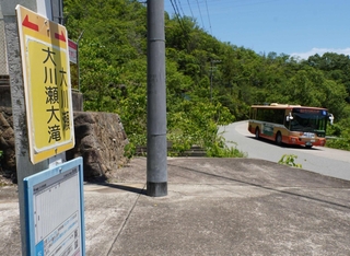「大川瀬大滝」バス停と、走る神姫バス＝三田市大川瀬