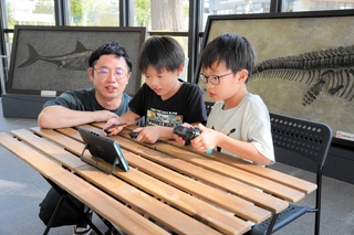 福本優研究員（左）と交流しながらゲームを楽しむ子どもたち＝三田市弥生が丘６