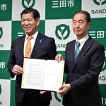 協定書を手にする田村克也市長（左）と阪急交通社の山川豊治社長＝三田市役所