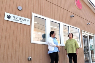 食料品店の運営などを手がける「赤心株式会社」社長の竹内いわ子さん（右）。建物の上部には「赤」のマークがある＝北海道浦河町荻伏町