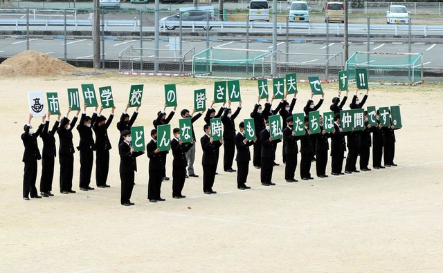 市川中学校の校舎に向かってプラカードでメッセージを送る市川高校の生徒たち＝市川町甘地（提供写真）
