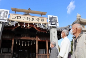 「コロナ終息祈願」と揮毫した額を見上げる三輪進さん（右）ら＝石海神社