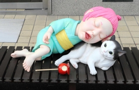 食べかけのりんごあめを放って猫にもたれかかる座敷わらし＝福崎町福崎新