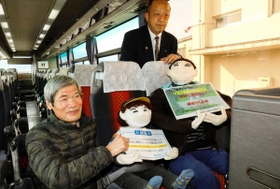 高速バスの最前列に座るかかしの親子を制作した岡上正人さん（左）＝宍粟市山崎町山田