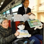 高速バスの最前列に座るかかしの親子を制作した岡上正人さん（左）＝宍粟市山崎町山田