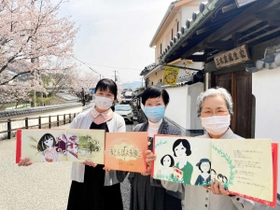 三木露風の生家前で絵本を紹介する筆者の浜田多代子さん（中央）ら＝たつの市龍野町上霞城