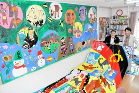 東京五輪の公式ＨＰに掲載された作品と塩飽康正さん（左）、隆子さん夫妻＝赤穂市大町