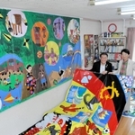 東京五輪の公式ＨＰに掲載された作品と塩飽康正さん（左）、隆子さん夫妻＝赤穂市大町