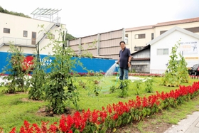 商店街の一角の畑で水やりをする安岡好光さん＝佐用町佐用