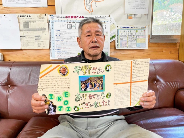 大学生から贈られた寄せ書きを手にする平野岩夫さん＝遊ファーム