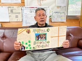 大学生から贈られた寄せ書きを手にする平野岩夫さん＝遊ファーム