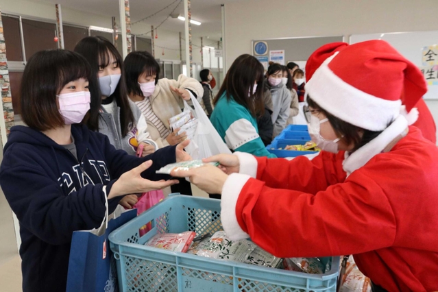 サンタクロース姿の職員から食品を受け取る学生ら＝相生市看護専門学校